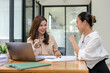 © Wasana - Two business women sit and discuss plans for a new project. Brainstorm and share ideas.