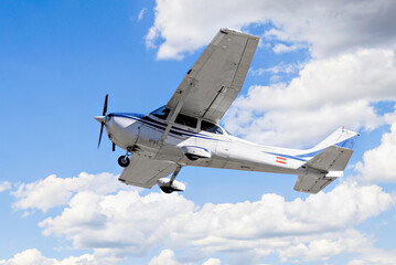 Single engine ultralight plane flying in the blue sky with white clouds	