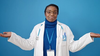 Canvas Print - African american woman doctor standing clueless over isolated blue background