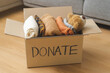 © KMPZZZ - Recycling, Donation for poor, packing object at home, putting on stuff into donate box with second hand clothes on floor at home, charity helping and needy people. Reuse recycle, moving.