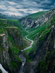 Canvas Print - Aerial view of a gorge with a river between rocky mountain slopes, and a waterfall in the background