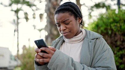 Poster - African american woman using smartphone with serious expression at park