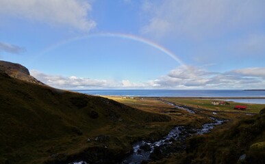 Beautiful scenery of rainbow with blue cloudy sky over the sea in Iceland