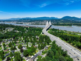 Sticker - Drone shot of Coquitlam cityscape with Port Mann Bridge and river under blue sky