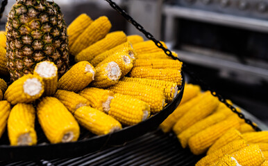 Wall Mural - Boiled corn and pineapple at street food market closeup. Fresh yellow vegetables maize and fruits at traditional fair festival