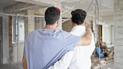 Wall Mural - Two men couple hugging each other looking around at construction site