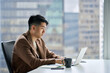 © insta_photos - Busy professional Asian business man working typing on laptop. Young Japanese serious businessman using computer technology thinking on finance corporate strategy in office sitting at window.