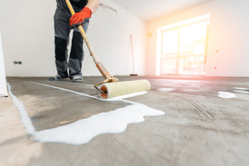 floor priming process. worker use primer on concrete floor before laying tiles, strengthening surfac