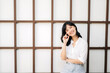 © Jirawatfoto - Portrait beautiful young asian woman happiness sitting on wooden grid wall, Happy female is smiling on wooden grid wall, wellness people concept.