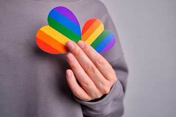 Rainbow heart from paper in woman hands. LGBT flag. LGBTQIA Pride Month in June. Lesbian Gay Bisexual Transgender. Gender equality. Human rights and tolerance. Rainbow flag