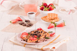Fototapeta Uliczki - Waffles with strawberries and chocolate cream.