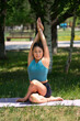 © Tatyana Orakova Орак - A young Asian (Kazakh) woman practices yoga in a city park in summer.