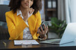 © SOMKID - African American businesswoman working on mobile phone with laptop computer and finance marketing chart, Advisor showing plan of investment to clients at office desk. Digital marketing online concept.