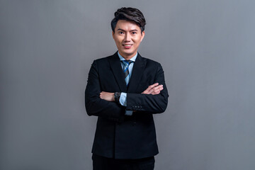 Confident Asian bossy businessman posing in professional formal black suit-clad on isolated background. Success corporate office worker for business promotion and advertisement. Jubilant
