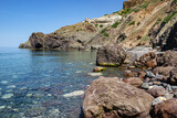 Fototapeta Morze - Black Sea coast, Cape Fiolent, Crimea, Ukraine. Royal beach. The sea has transparent turquoise water. There are large smooth stones on the shore.