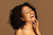 © Prostock-studio - Laughing sensual half-naked black lady touching her chin, brown background