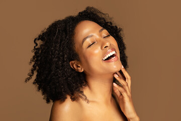 Wall Mural - Laughing sensual half-naked black lady touching her chin, brown background