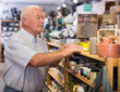 © JackF - Portrait of focused senior man choosing dishware at store