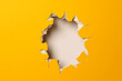 torn hole in the white wall of paper on a yellow background