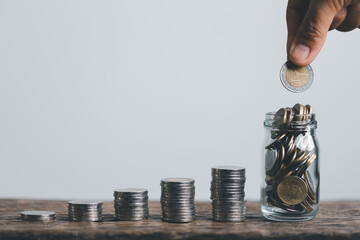 Wall Mural - Business asian woman hand put coins in piggy bank on wood table background, saving money wealth and financial concept, finance, investment, Financial planning.Financial planning deposit for retirement