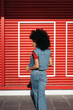 © Scopio - Woman in blue denim vest standing near red roll up door