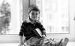 © alexkich - The little boy is reading a book. The child sits at the window and prepares for lessons. Boy with a book in his hands is sitting on the windowsill.