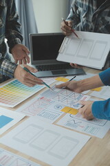 Close up ux developer and ui designer brainstorming about mobile app interface wireframe design on table with customer breif and color code at modern office.Creative digital development agency