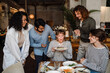 © Drobot Dean - Young woman surrounded by friends blowing candles on cake during birthday party in restaurant