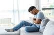 © Graphicroyalty - A man suffers from abdominal pain while sitting at home on the couch. Young man suffering from abdominal pain sitting on the couch at home.