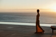 © KOTO - Woman looking at ocean from modern patio at sunset