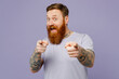 Young redhead bearded man wear violet t-shirt casual clothes point index finger camera on you motivating encourage isolated on plain pastel light purple background studio portrait. Lifestyle concept.