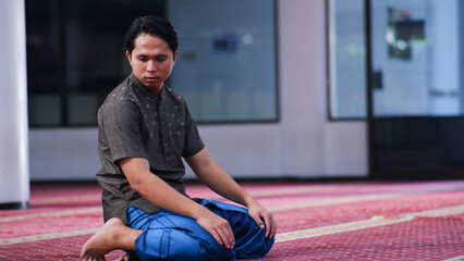 a muslim asian man is sitting tasyahud to perform the prayer