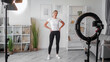 © golubovy - Fitness vlogging. Filming workout. Athletic woman perfect body filming sport training shooting on camera tripod using light equipment exercising in home interior.