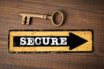 Wall Mural - secure concept. direction arrow with text and golden key on wood texture background
