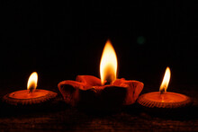 Burning Candles In Earthenware Bowls With Orange Fire On The Floor.