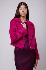 Wall Mural - Fashion photo of a beautiful elegant young asian woman in a pretty pink fuchsia dress, jacket posing on white, soft gray background. Studio Shot, portrait. Slim figure. 