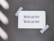 Paper note stick on wallpaper background with text Words can hurt Words can heal - to remind language have power to harm or heal - word choice matters most so choose wisely