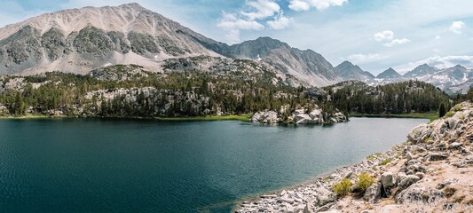 Panoramic shot of a Mammoth mountain lake with snowy trees and mountains in the background