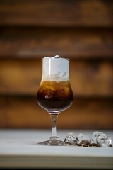 Wall Mural - Glass of iced coffee with cream against a wooden wall