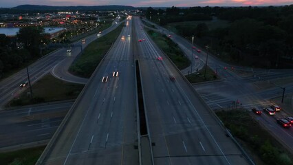 Wall Mural - Traffic at night. Aerial hyper lapse of highway interchange during sunset. Drone orbiting timelapse as dusk approaches.