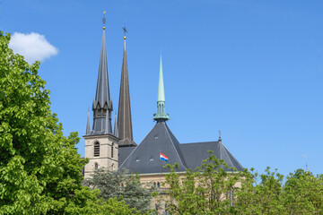 Wall Mural - Fragment of the main cathedral of Luxembourg. The spiers of the towers of the central cathedral against the backdrop of a bright spring sky and fresh foliage of trees.