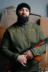 Wall Mural - Portrait of the armed bearded man looking with a serious face straight at the camera