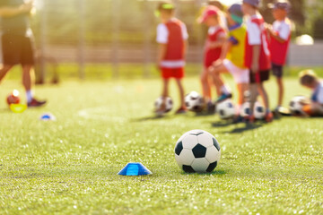 Wall Mural - Soccer, training and children on sports field. Football equipment at sports grass pitch. Soccer ball and training cone marker on the pitch. Children on sports practice