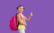 © Studio Romantic - Smiling schoolgirl with backpack and books isolated on purple studio background show thumb up excited about school start. Happy girl pupil with notebooks recommend online study course. Education.