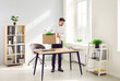 © Studio Romantic - Fired male employee emptying his desk, making room for new worker. Young man standing by his former working desk in office and putting his belongings such as folders and green plants in cardboard box