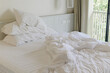an unmade white bed in bedroom