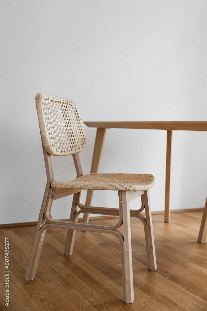 Wooden dining table with wicker chairs in light room