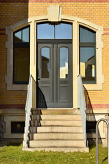 Wall Mural - View of brick building with black wooden door and steps