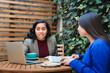 © padnob - Financial Security Conversation: Young Latina Woman Selling Life Insurance to Another Woman at a Cozy Cafe