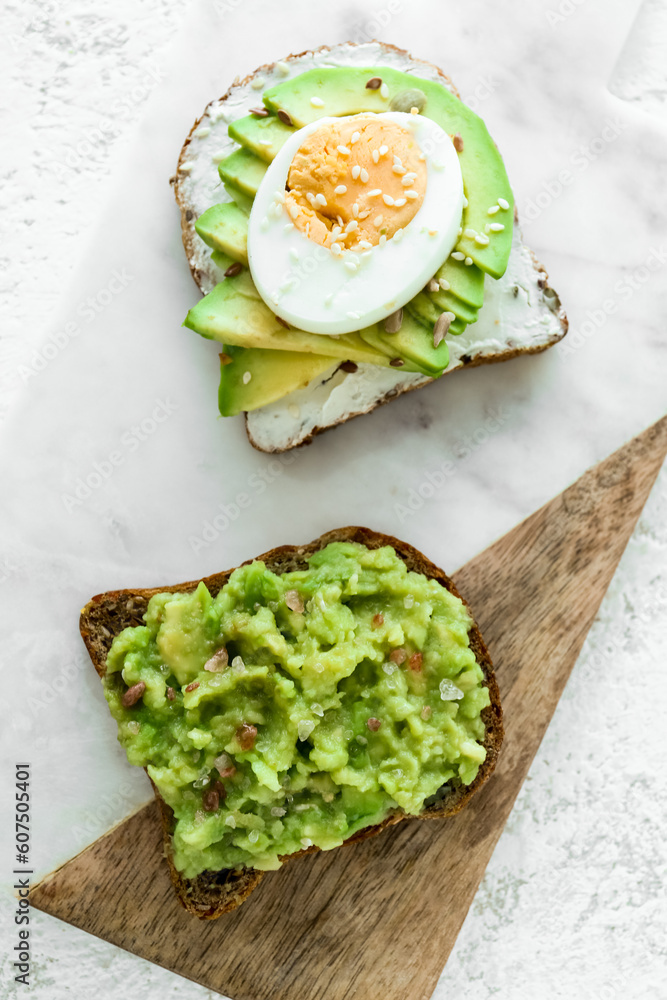 Board of tasty avocado toasts on light background